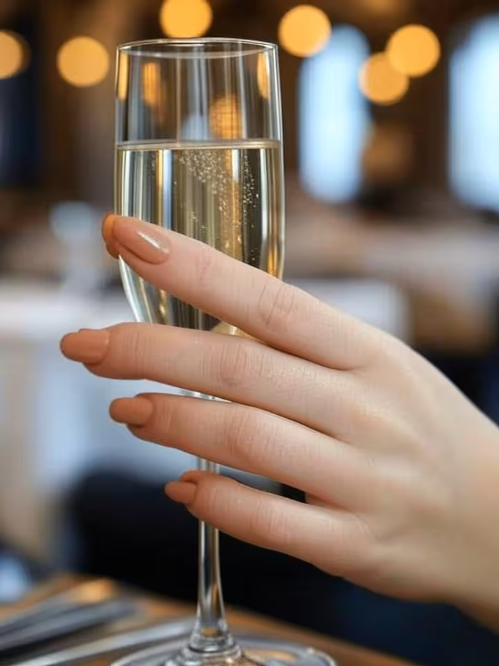 Perfect manicure holding champagne glass at luxury restaurant, elegant nude gel nails, sophisticated